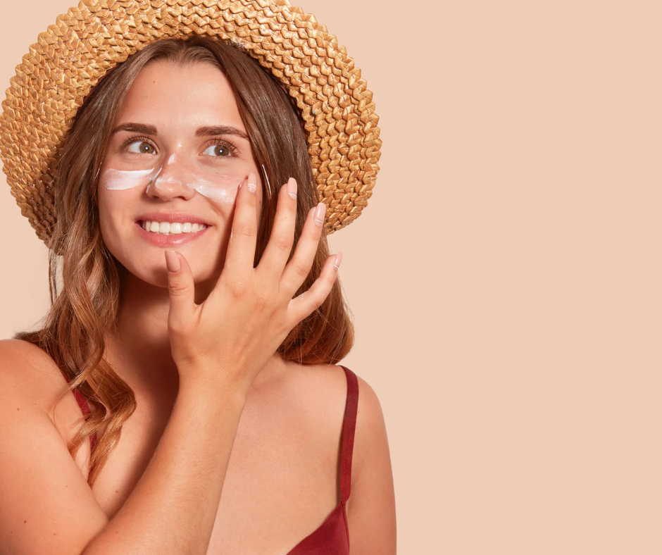 woman in straw hat applying sunscreen to her face